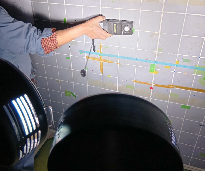 人工太陽照明灯（XC-500）で、対象面に光を照射し、その奥で照度計を手に持っている様子。